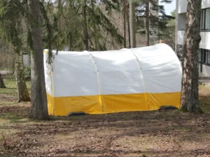 Arbetstält utifrån. Vitt tak med gul botten på sidorna. Mäter 6 x 6 meter och 3 meter i tak mitt på gaveln.